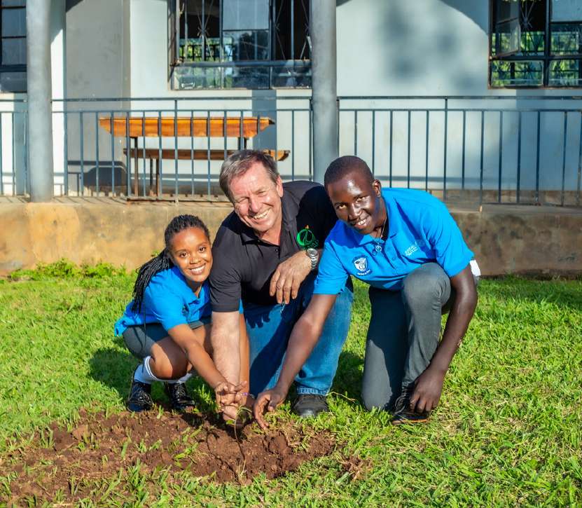 A student and tree-planting partners planting a seedling at Christ the King High School, Bweya, Entebbe.